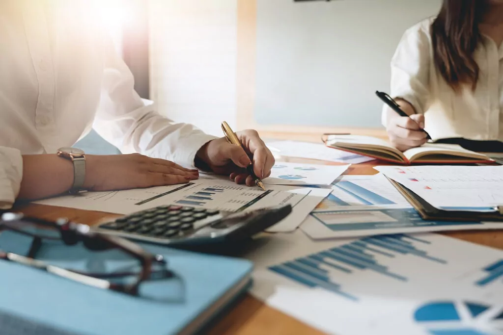 Business people sitting at a table with lots of financial paperwork spread out around them