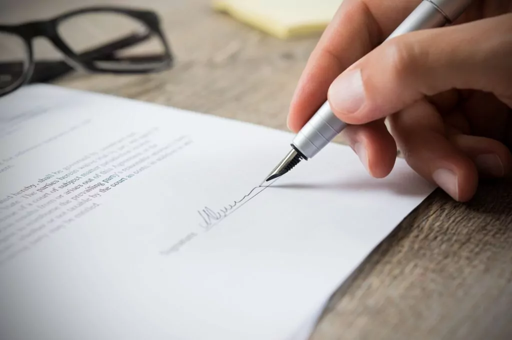 Close up of a person's hand while signing a document